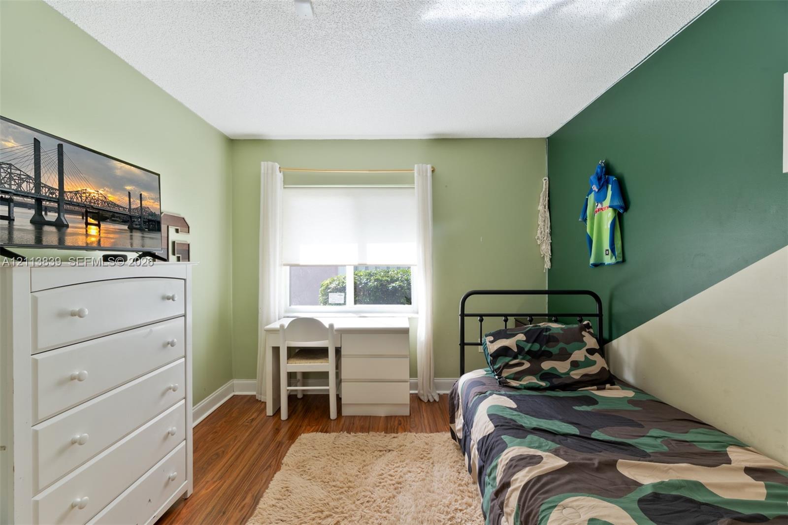 Wood-finish flooring and dual-tone painted walls featuring a window with roller shade