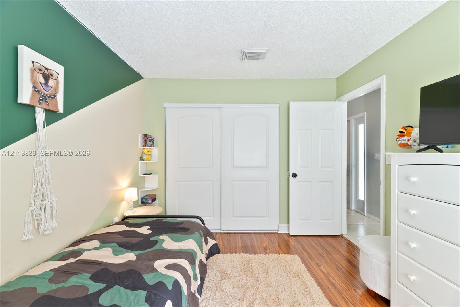 Wood-finish flooring, dual sliding closet doors with raised panels, built-in corner shelving, and a six-panel interior door