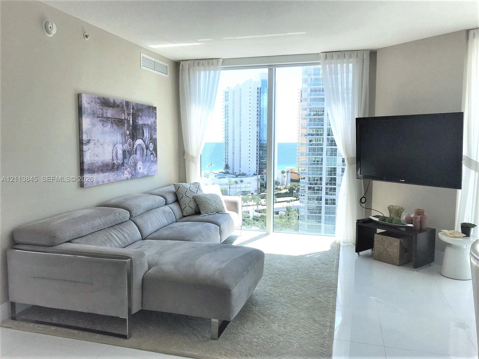 Floor-to-ceiling windows, polished white flooring, and neutral wall tones