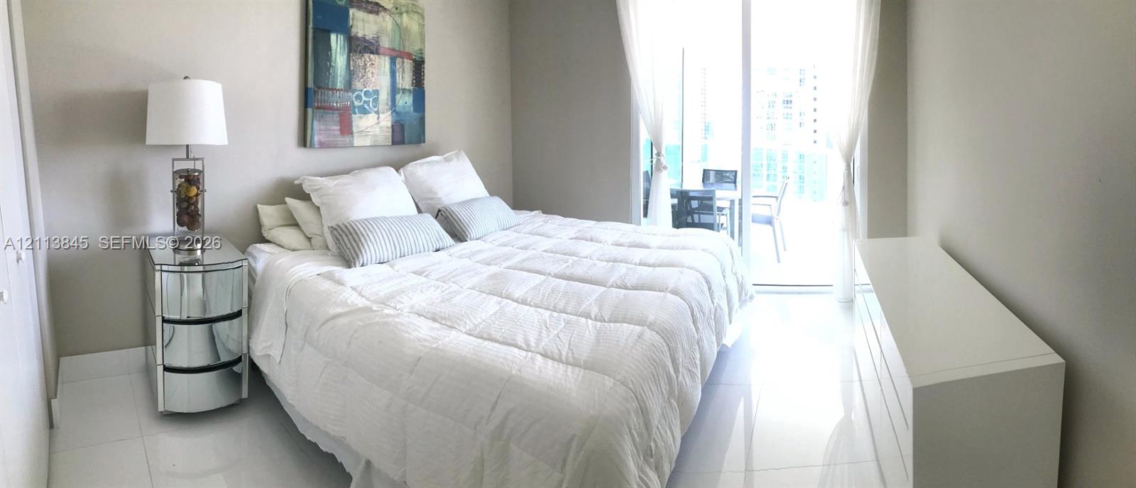 Spacious interior featuring white tile flooring, neutral wall tones, and glass sliding doors providing external access
