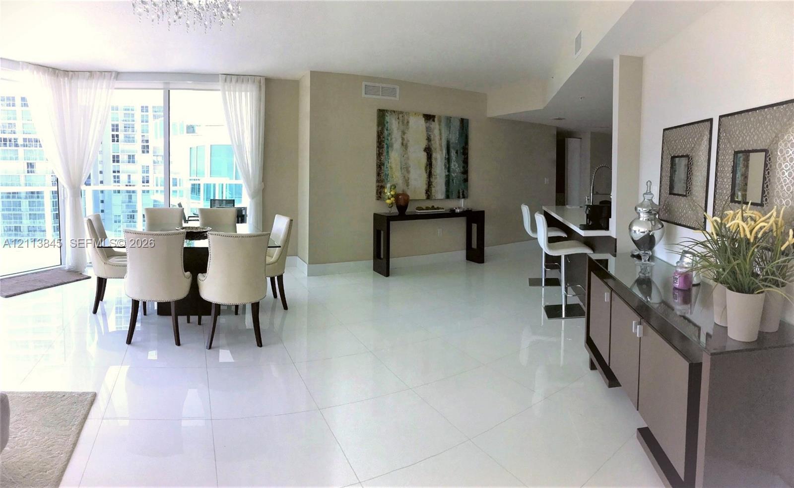 Open-concept living space featuring high-gloss tile flooring, floor-to-ceiling windows, and a built-in kitchen breakfast bar Open-concept living space featuring high-gloss tile flooring, floor-to-ceiling windows, and a built-in kitchen breakfast bar