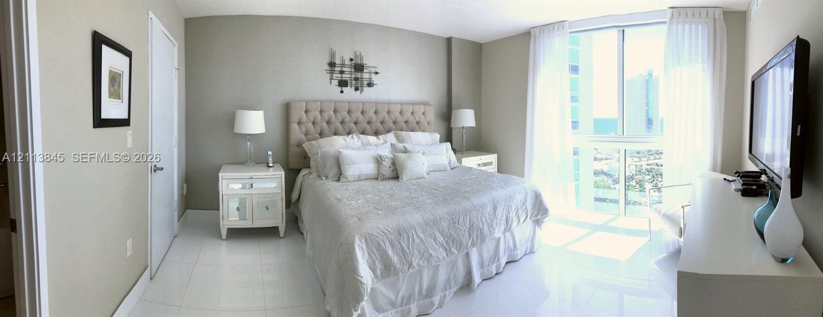 Floor-to-ceiling windows with neutral drapery, large-format tile flooring, and smooth-finish walls Floor-to-ceiling windows with neutral drapery, large-format tile flooring, and smooth-finish walls