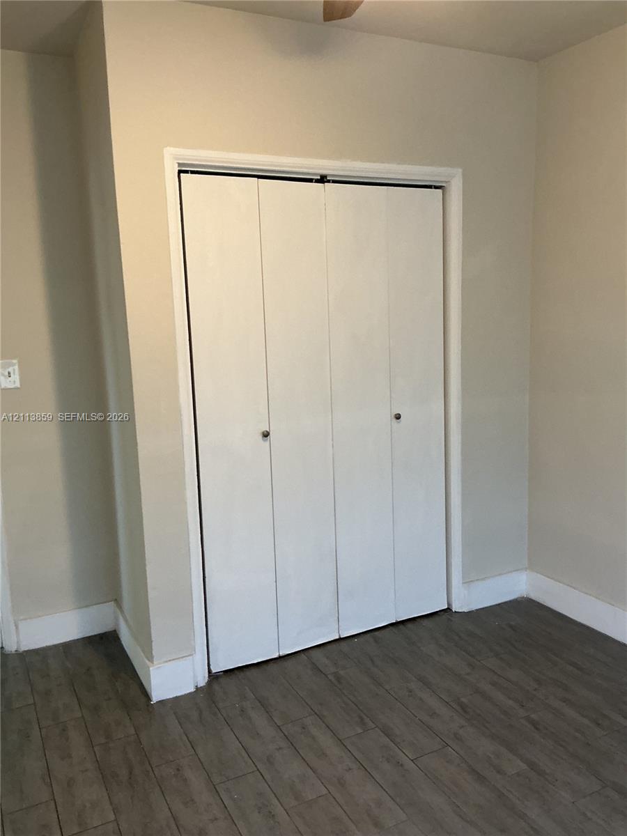 Closet featuring white bi-fold doors with circular hardware and wood-finish flooring