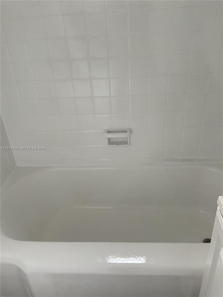 Bathtub surround featuring white square ceramic tile and a built-in recessed soap dish