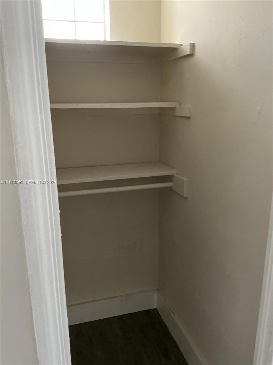 Storage closet featuring wood-finish flooring, two fixed shelves, and a built-in hanging rod