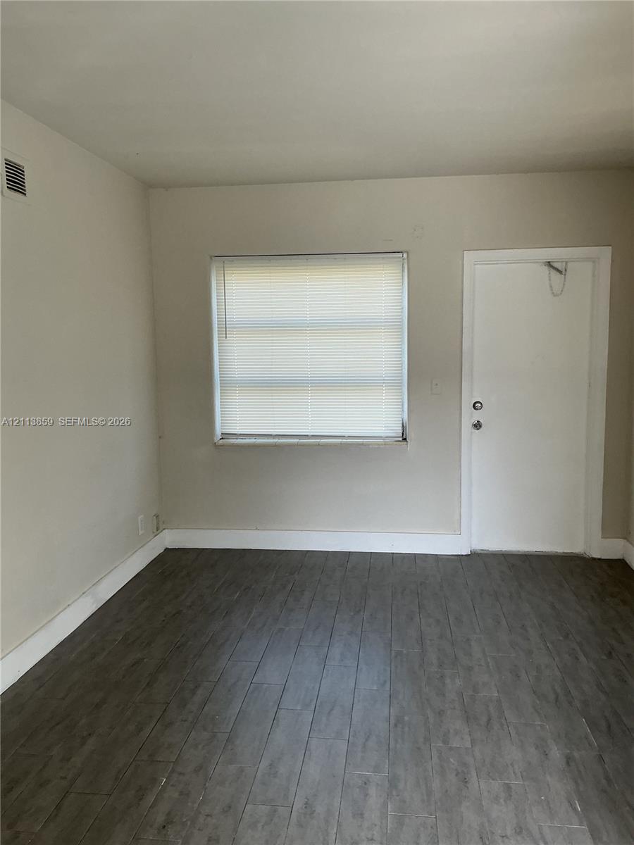 Wood-finish flooring, neutral wall tones, and single-pane window with horizontal blinds