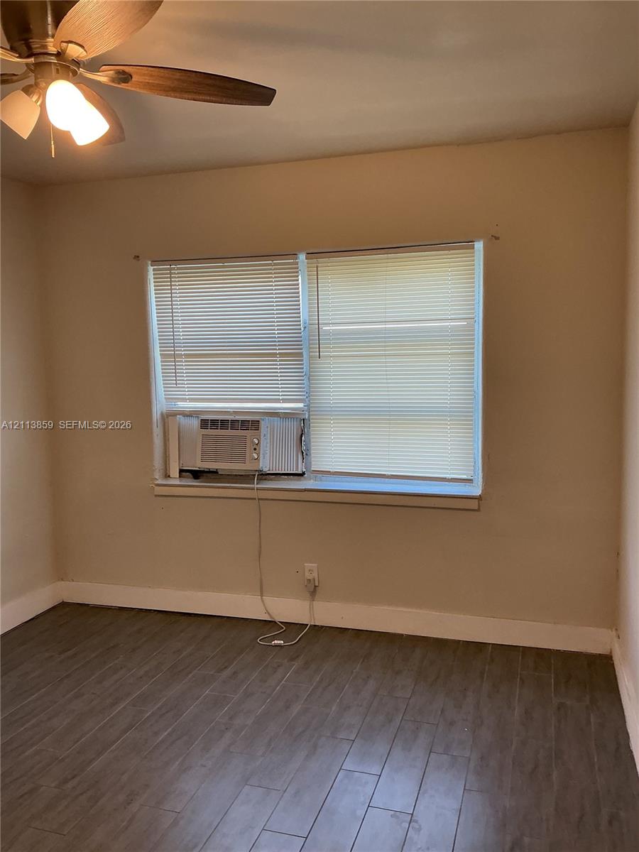 Wood-finish flooring, multi-pane window with installed blinds, and ceiling fan with integrated lighting