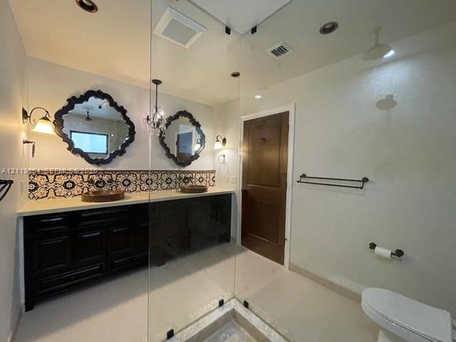 Dark wood dual vanity with light stone countertop, patterned ceramic tile backsplash, two decorative wall mirrors, and glass-enclosed shower