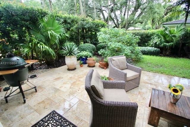 Stone paver patio featuring integrated landscaping with mature palm trees and manicured shrubbery