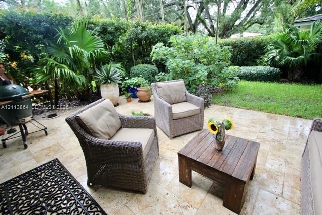Stone paver patio featuring established perimeter landscaping, mature trees, and a grass lawn