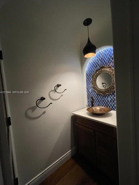 Vanity featuring a stone-look countertop, a bronze-finish vessel sink, and an arched mosaic tile backsplash