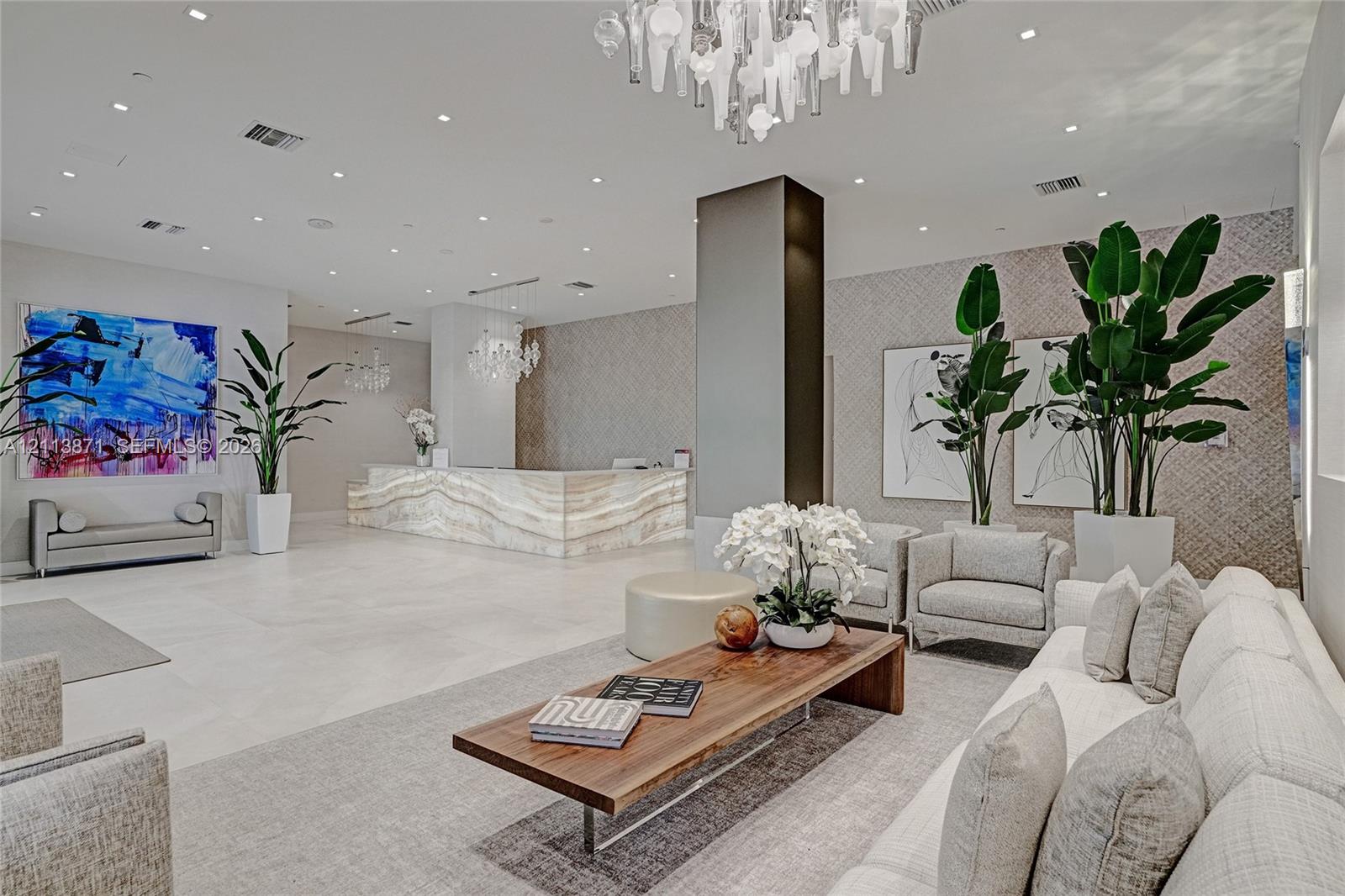 Lobby featuring a stone-faced reception desk, recessed ceiling lighting, textured wall coverings, and a tiered glass chandelier Lobby featuring a stone-faced reception desk, recessed ceiling lighting, textured wall coverings, and a tiered glass chandelier