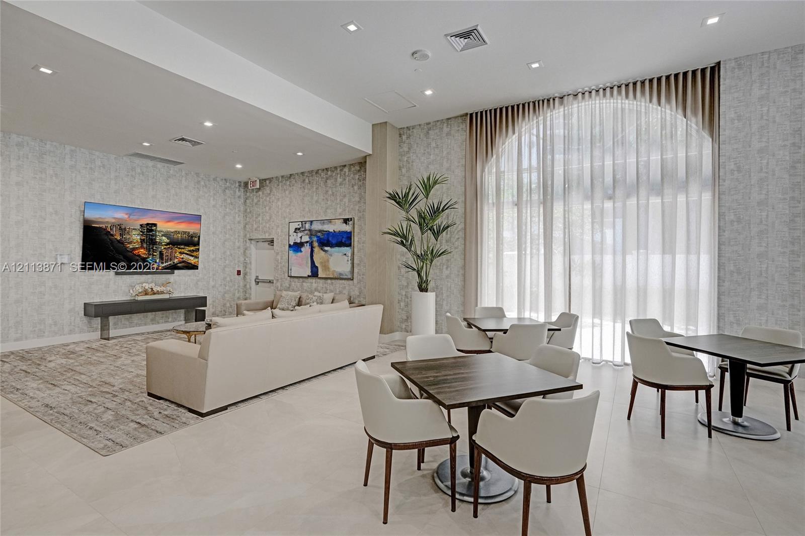 Common space featuring high ceilings, floor-to-ceiling arched windows, patterned wall coverings, recessed lighting, and large-format tile flooring Common space featuring high ceilings, floor-to-ceiling arched windows, patterned wall coverings, recessed lighting, and large-format tile flooring