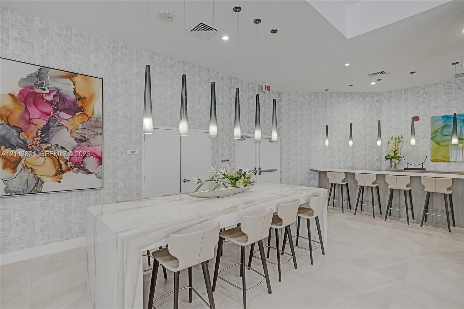Waterfall-edge island with stone-finish countertop, minimalist pendant lighting, tiled flooring, and textured wall covering Waterfall-edge island with stone-finish countertop, minimalist pendant lighting, tiled flooring, and textured wall covering