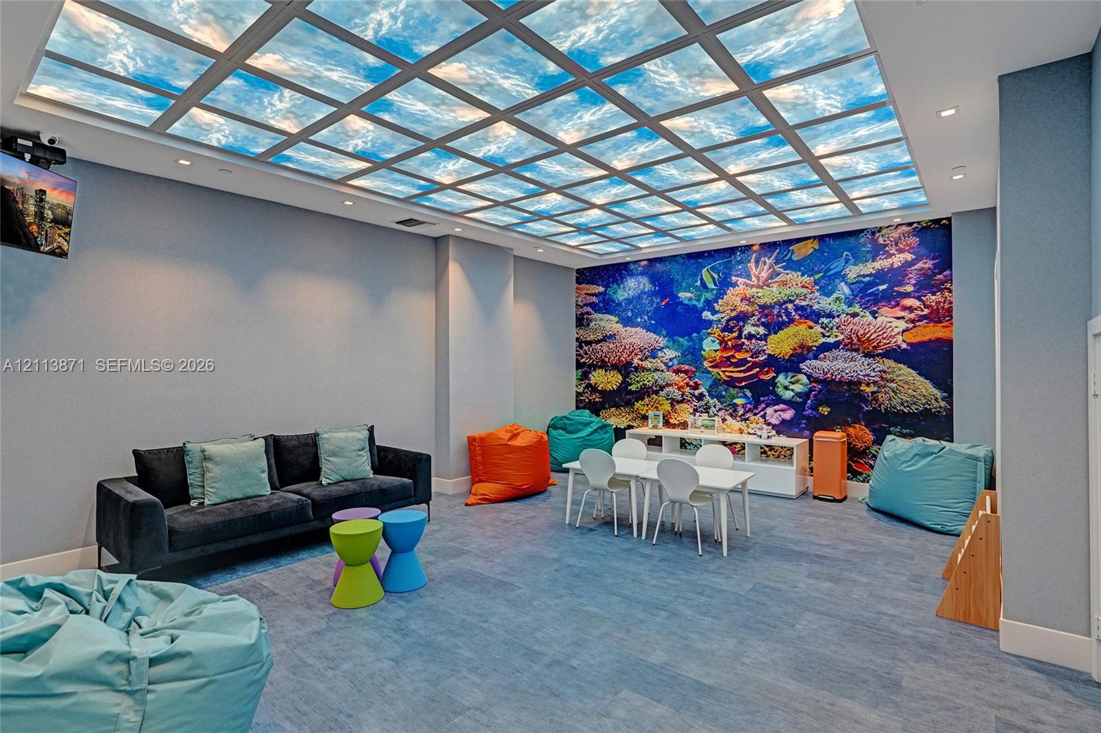 Customized grid ceiling panel with sky-pattern graphic, large-scale coral reef wall mural, recessed ceiling lighting, and blue-toned flooring Customized grid ceiling panel with sky-pattern graphic, large-scale coral reef wall mural, recessed ceiling lighting, and blue-toned flooring