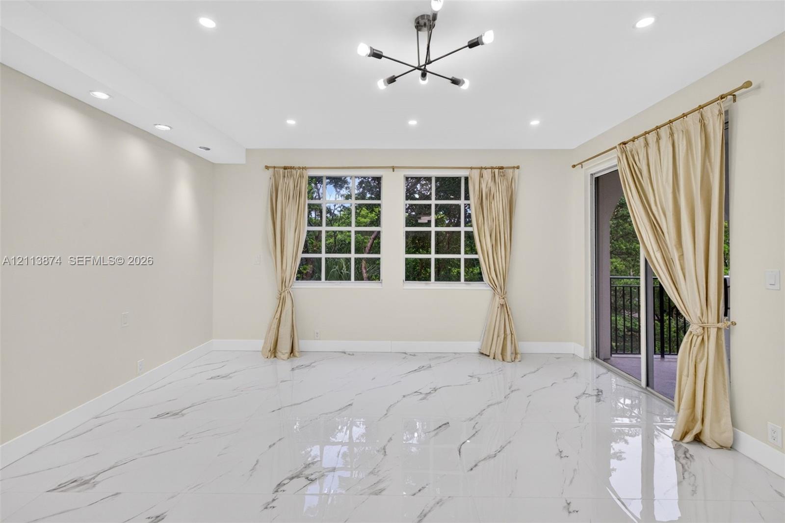 Polished stone-finish flooring, modern sputnik-style chandelier, recessed lighting, multi-pane windows, and sliding glass door