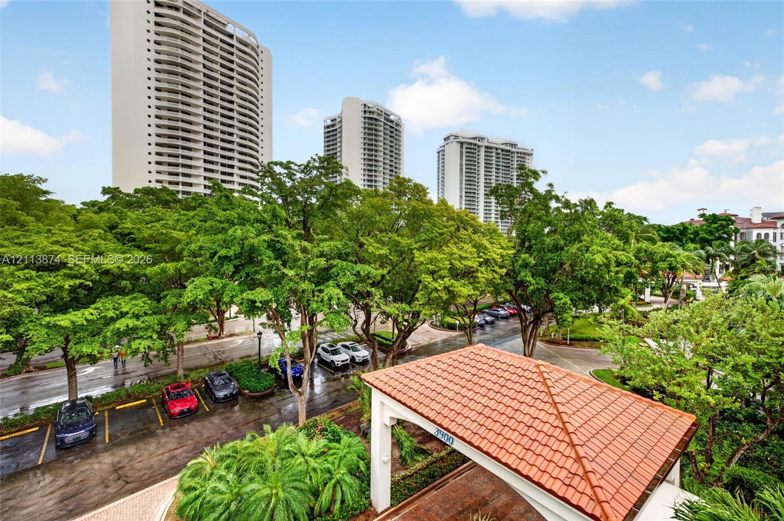 High-rise residential towers featuring multi-story architectural design, terracotta-tiled porte-cochre, paved driveways, and expansive mature landscaping