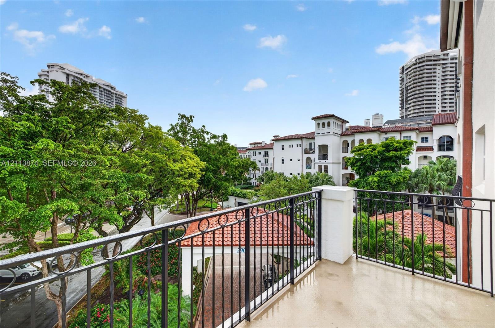 Private balcony featuring metal railings, smooth-finish flooring, and a terra cotta tile roof structure