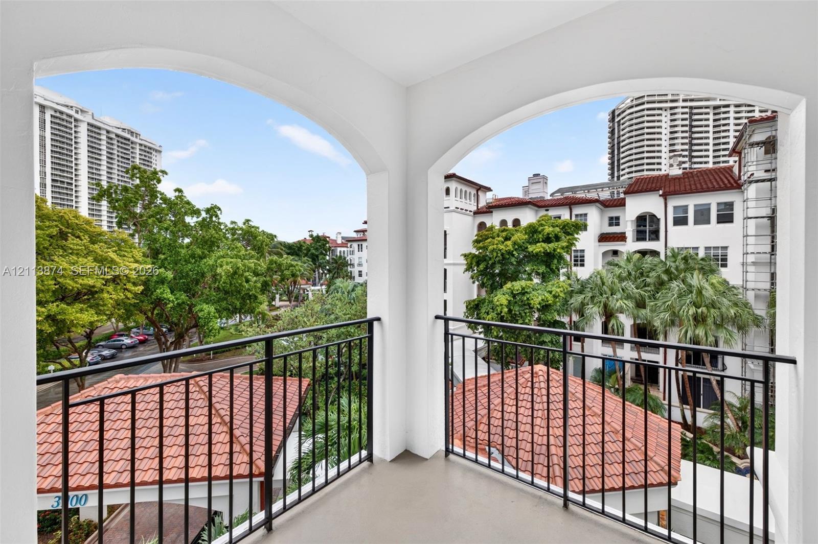 Covered balcony featuring arched architectural openings and black metal railings
