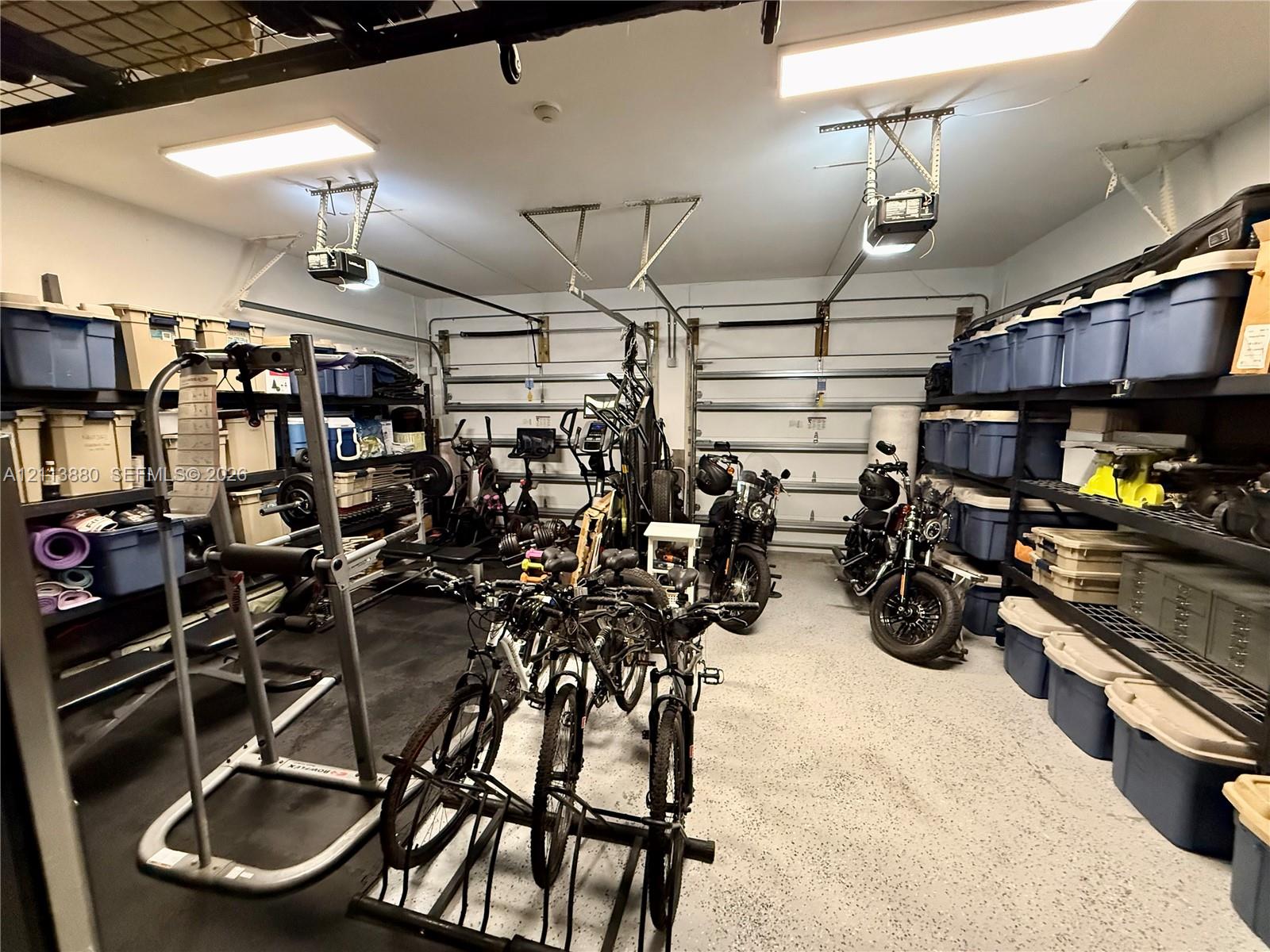 Two-car garage featuring epoxy-coated flooring, dual automatic door openers, and wall-mounted metal shelving units