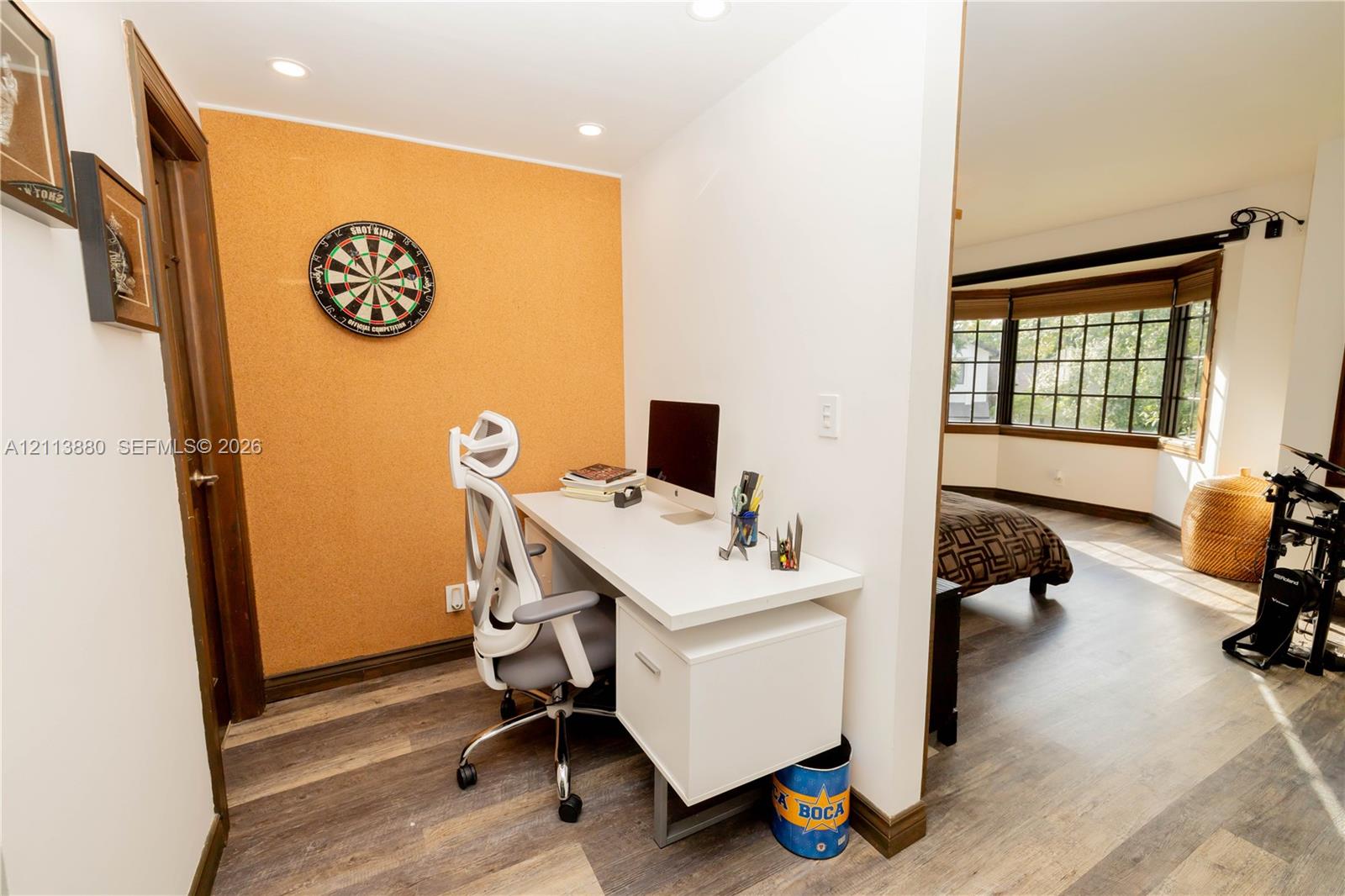 Built-in desk with integrated storage cabinetry, wood-finish flooring, recessed lighting, and a multi-pane bay window