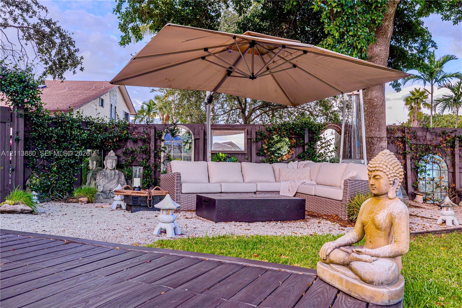 Outdoor living area featuring a wooden deck, crushed stone ground cover, and a dark-toned privacy fence with inset decorative mirrors