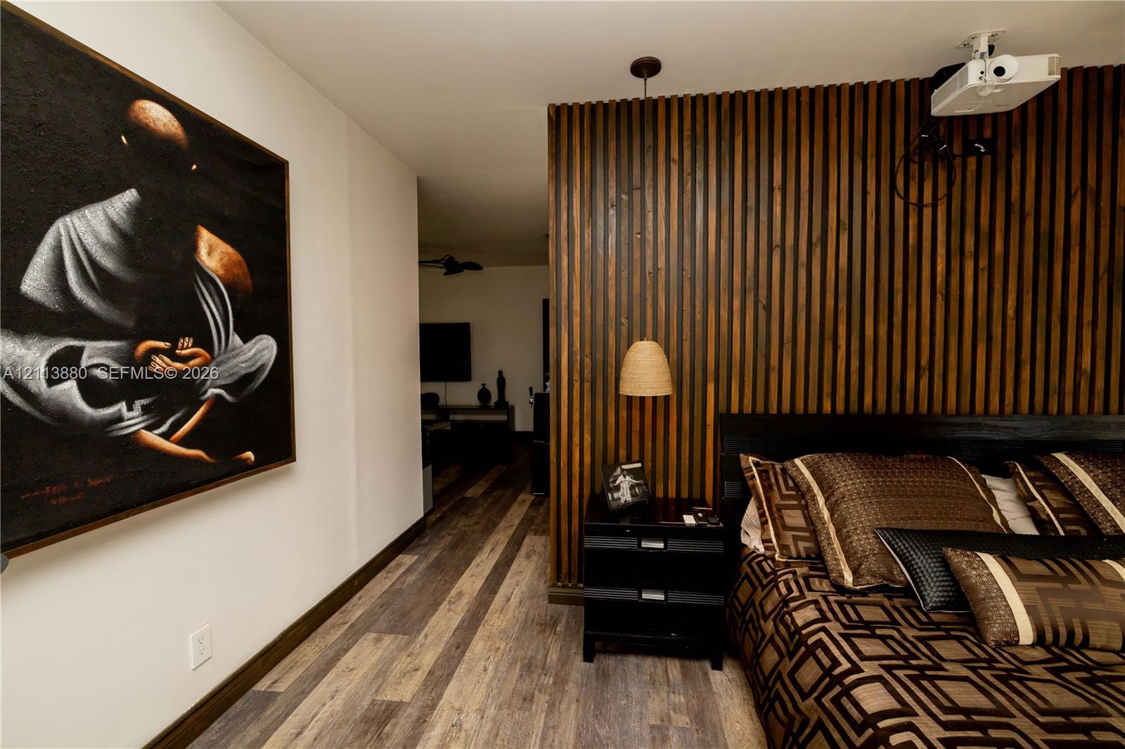Vertical wood slat accent wall featuring a hanging pendant light and multi-toned wood-finish flooring