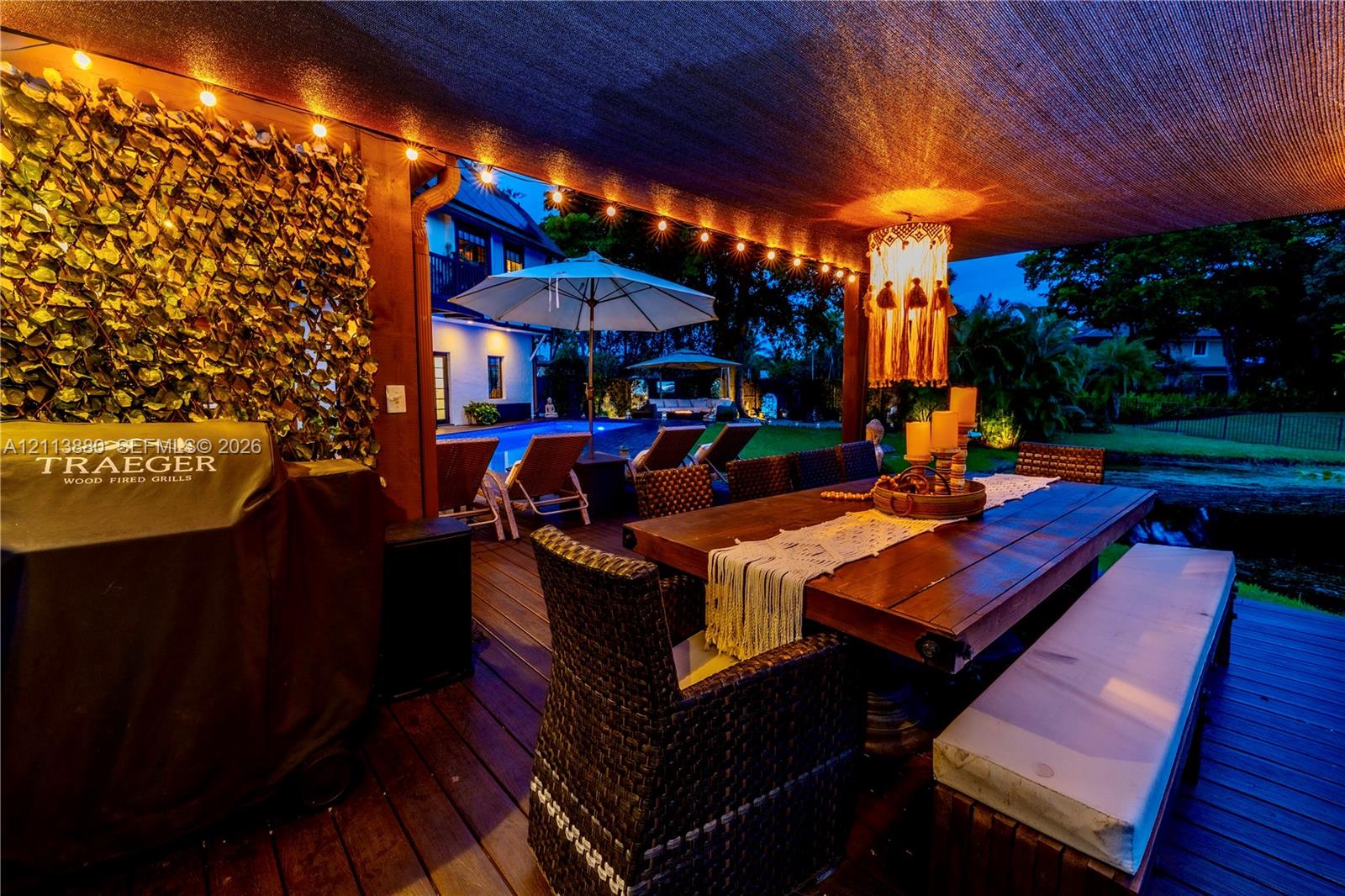 Covered outdoor deck featuring wood-finish decking, integrated string lighting, and a privacy screen with decorative faux foliage