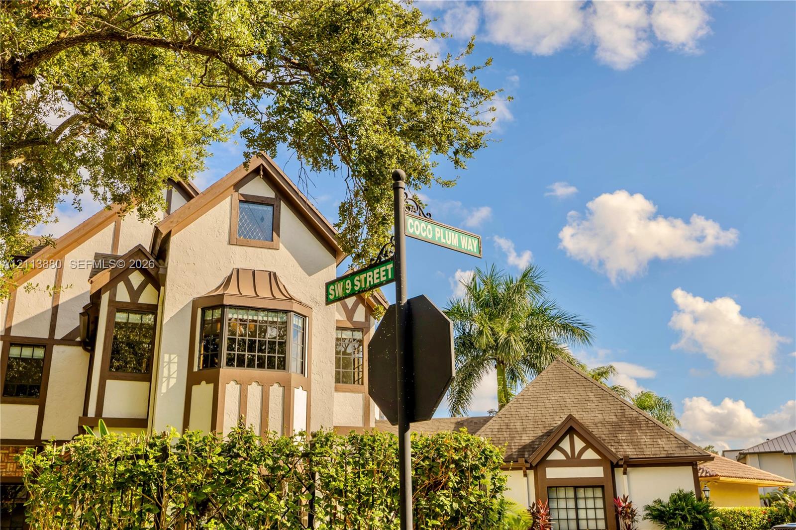 Tudor-style exterior featuring stucco facade with timber framing, multi-pane bay windows, and mature landscaping