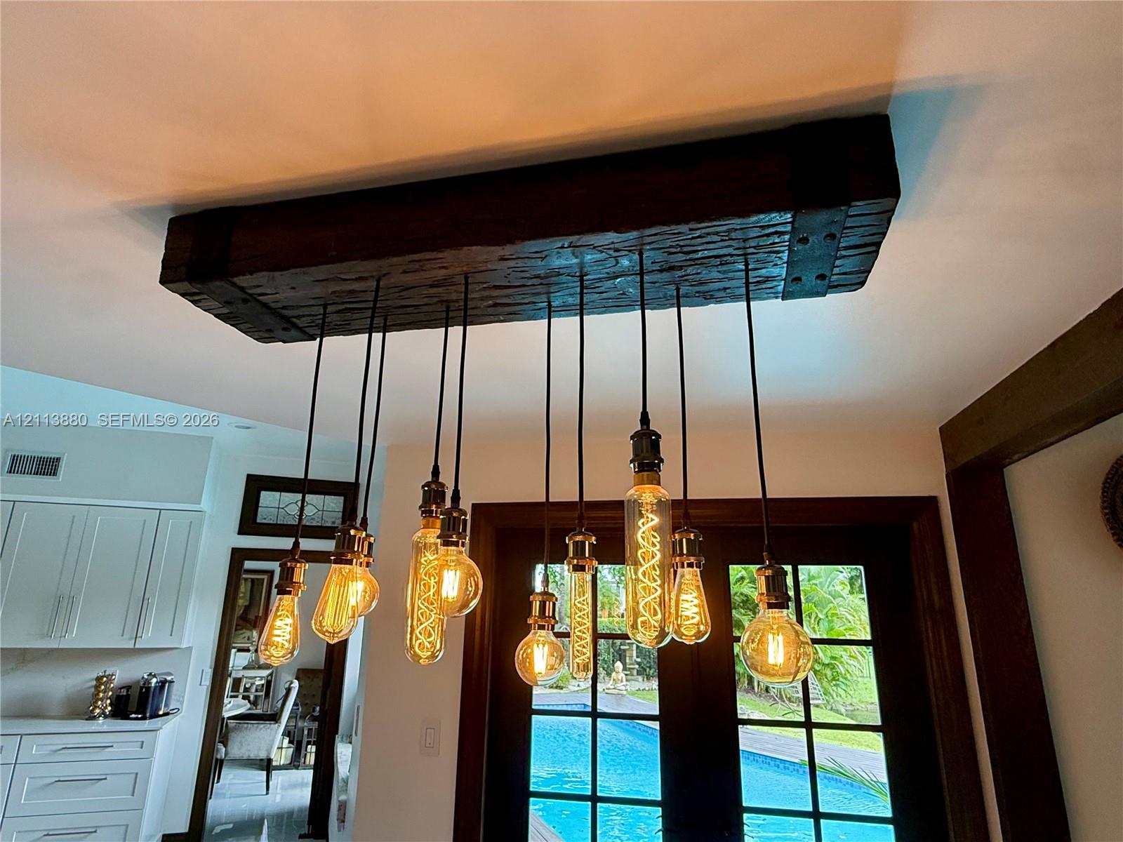 Custom industrial-style light fixture featuring a rustic reclaimed wood beam housing and a multi-pendant arrangement with exposed filament bulbs