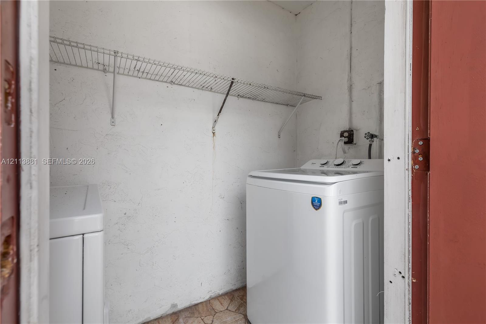 Laundry space featuring wall-mounted wire shelving and dedicated water hookups