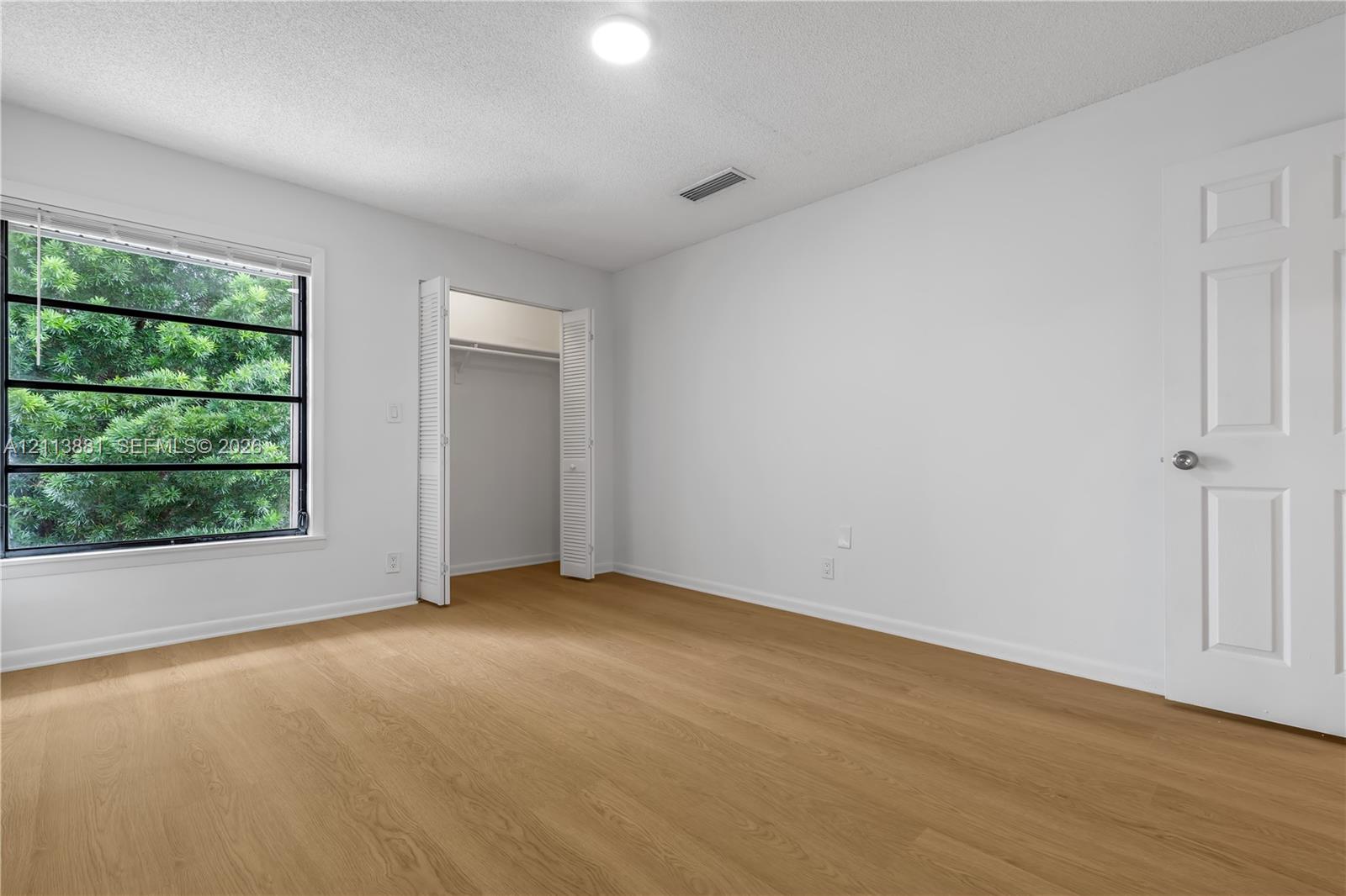 Wood-finish flooring, multi-pane window with exterior greenery, and bi-fold closet doors