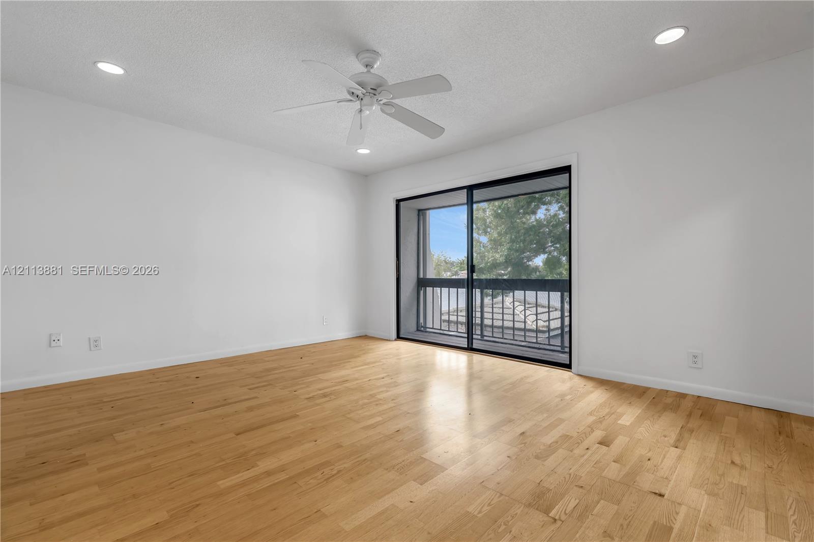 Wood-finish flooring, recessed lighting, white walls, ceiling fan, and sliding glass door with balcony access