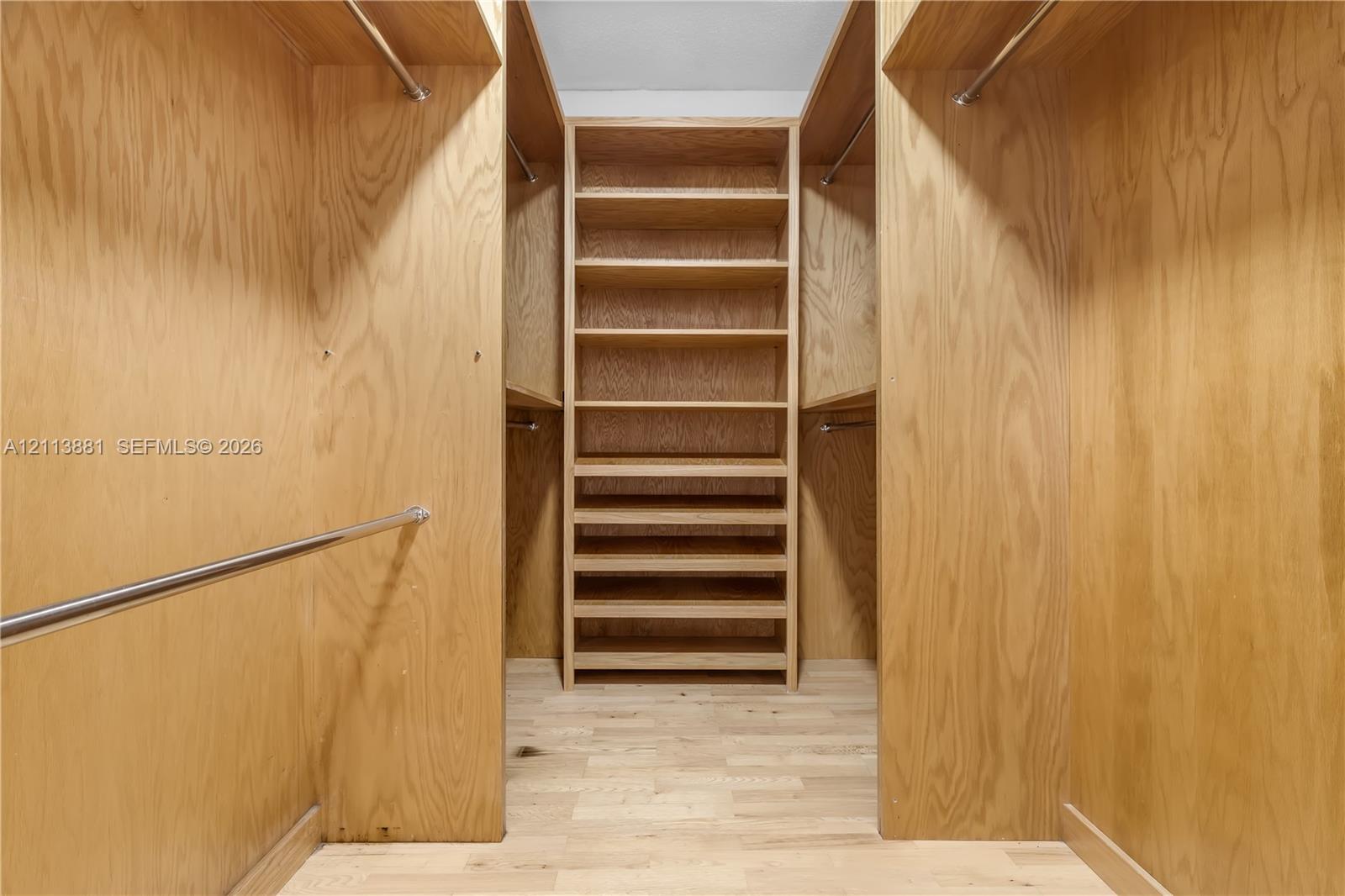 Walk-in closet featuring custom wood-finished cabinetry, integrated shelving, tiered storage drawers, and metal clothing rods