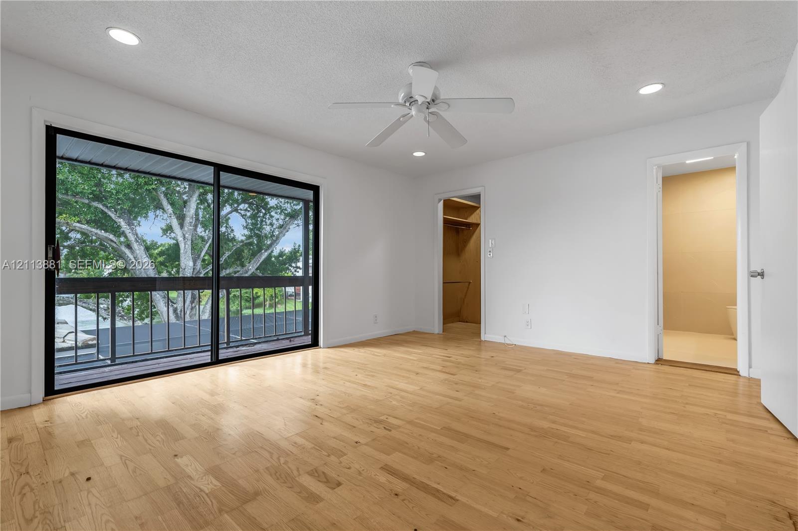 Room featuring wood-finish flooring, recessed lighting, a ceiling fan, and black-framed sliding glass doors opening to an exterior balcony