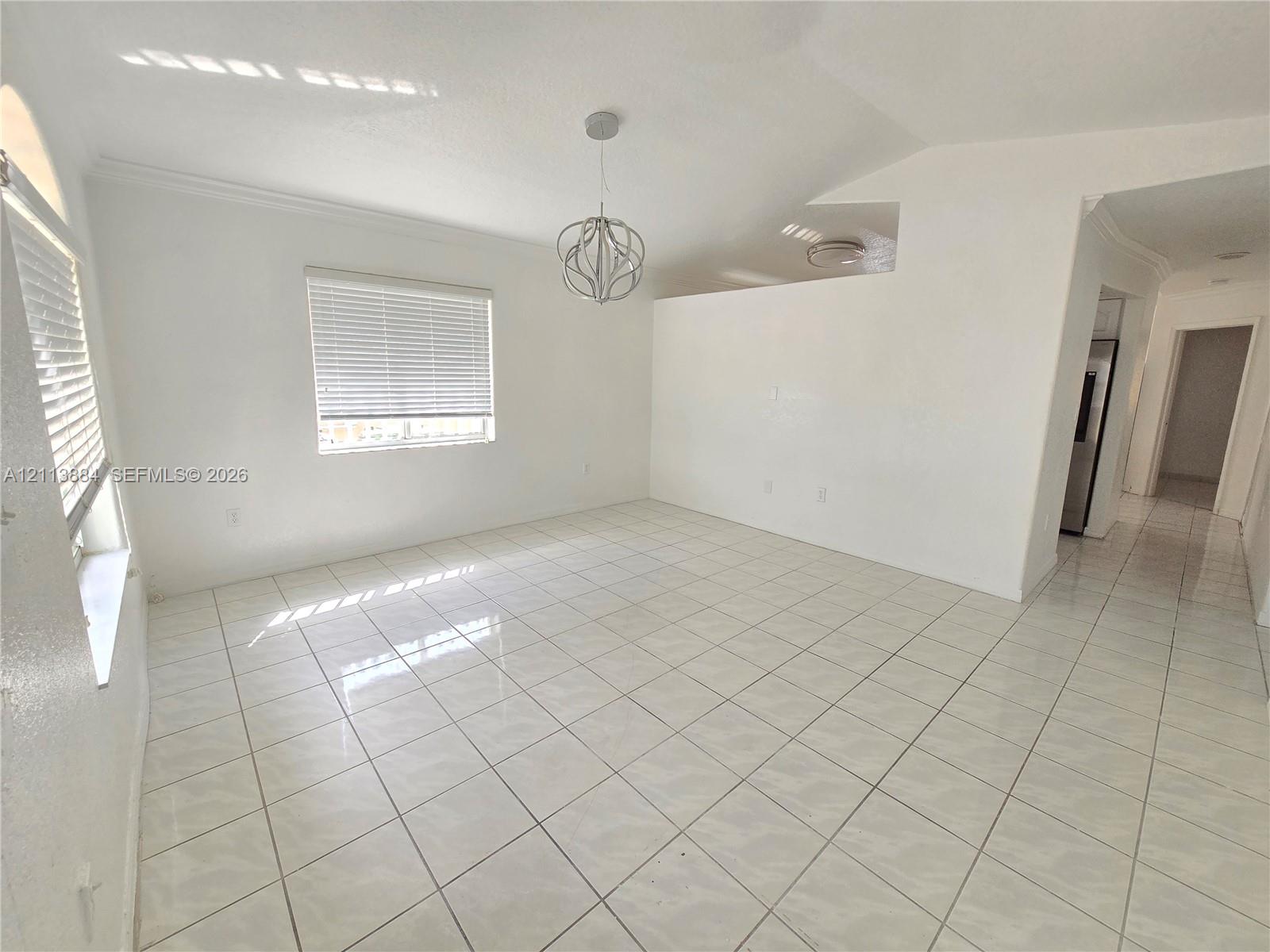 Open-concept room featuring light tile flooring, high vaulted ceilings, architectural archway accents, and a contemporary spherical pendant light fixture