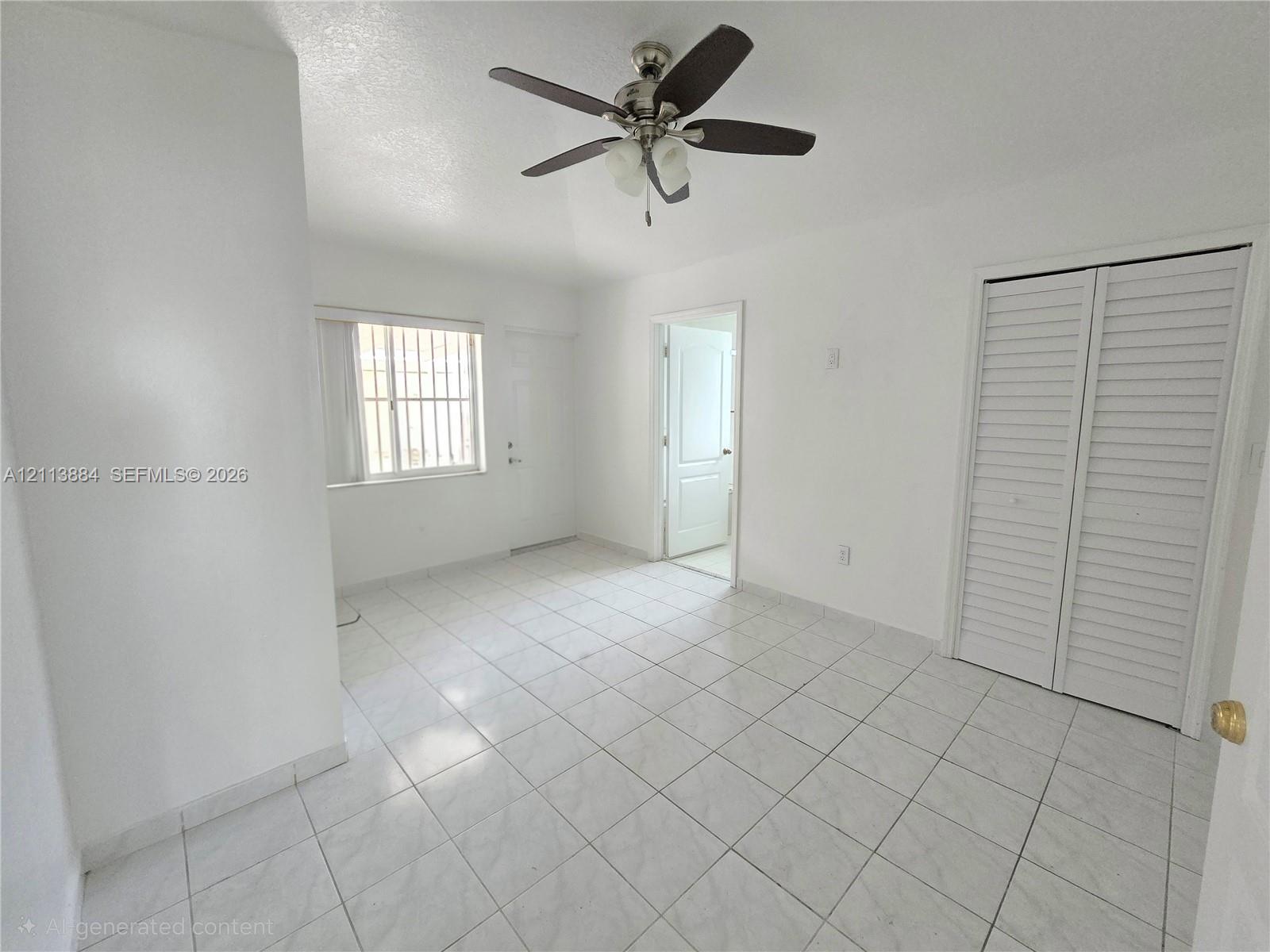 Interior room featuring tile flooring, ceiling fan with light fixture, louvered closet doors, and multi-pane window