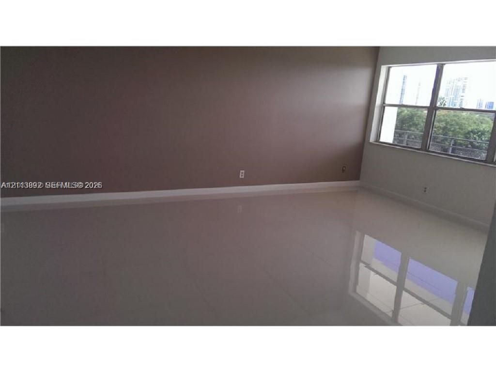 Spacious room featuring polished neutral-toned tile flooring and a large multi-pane window