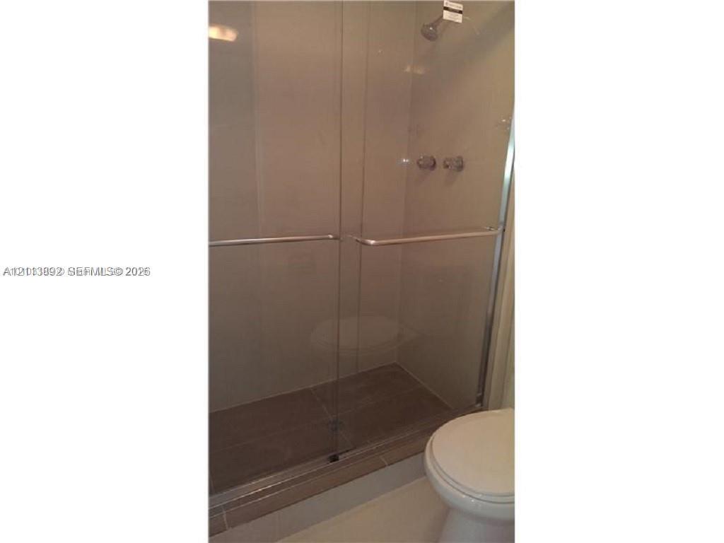 Walk-in shower featuring a glass-panel enclosure, metallic hardware, and neutral-toned wall tiling