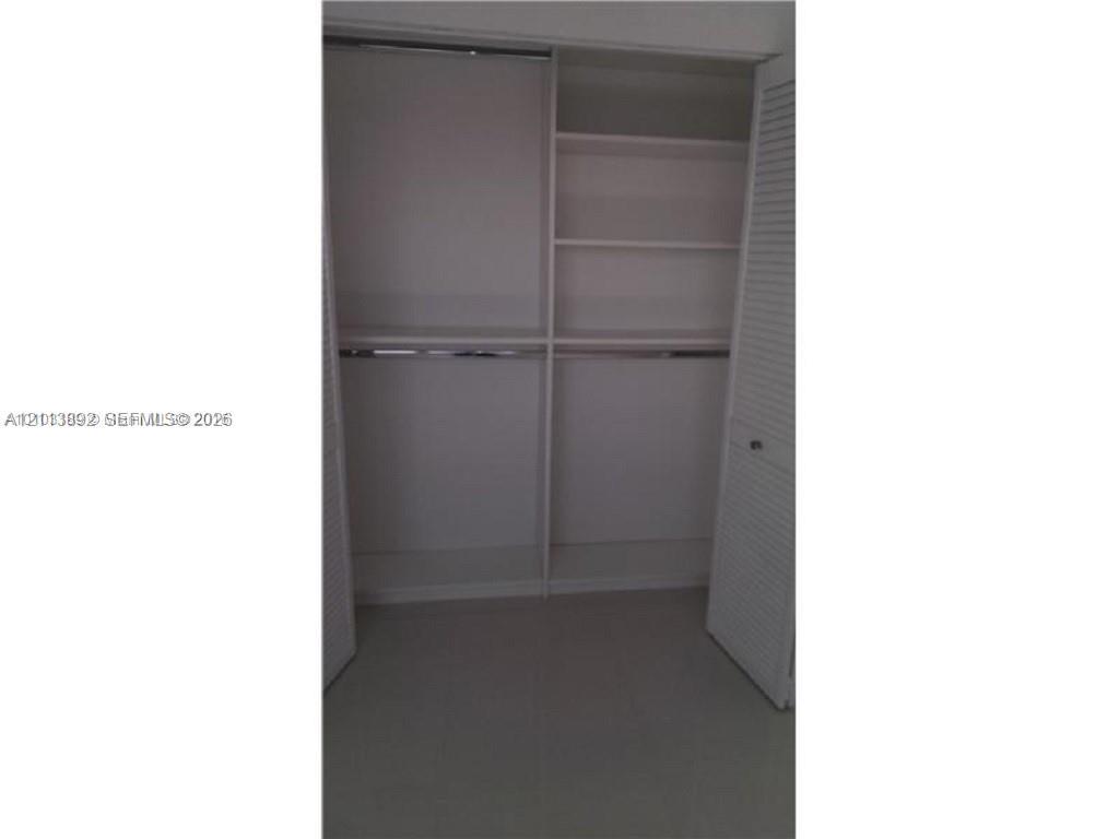 Closet featuring louvered bifold doors, integrated shelving, and dual hanging rods