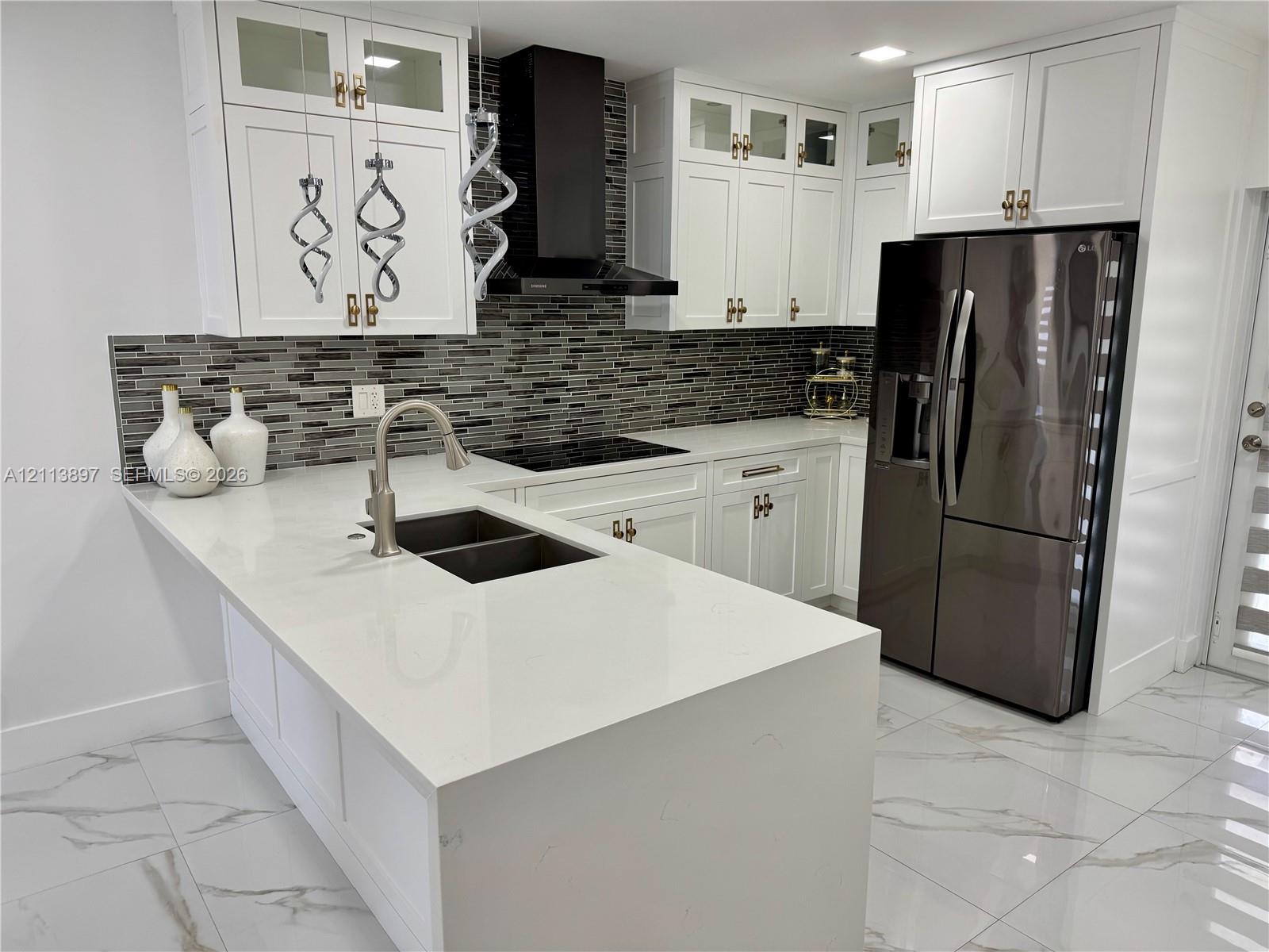 Kitchen featuring white cabinetry, quartz countertops, a mosaic tile backsplash, a stainless steel undermount sink with a gooseneck faucet, and large-format tile flooring