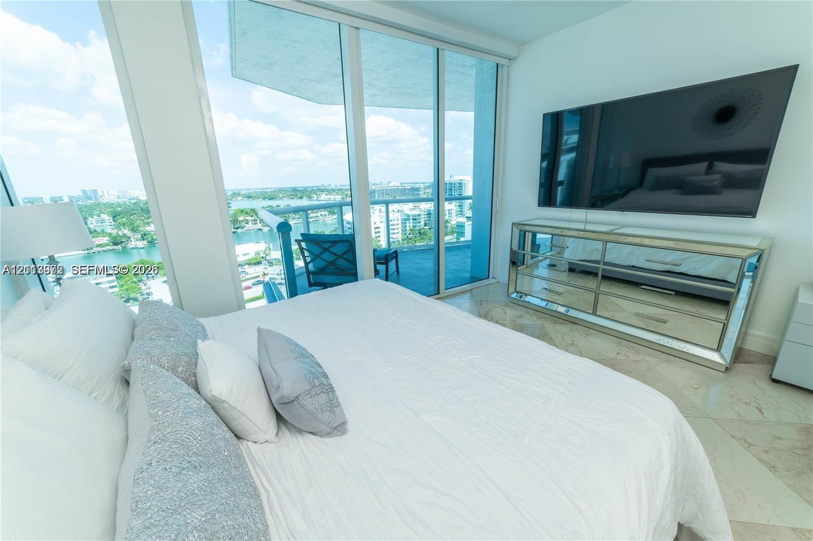 Floor-to-ceiling glass sliding doors, private balcony, tile flooring, and neutral wall finishes