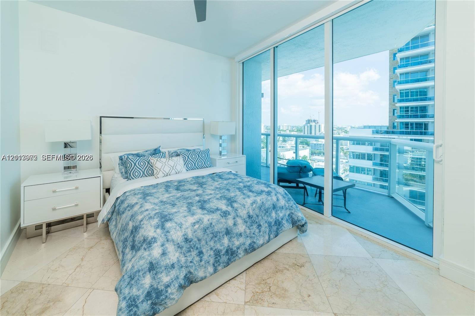 Floor-to-ceiling sliding glass doors, private balcony with glass railing, and polished stone tile flooring