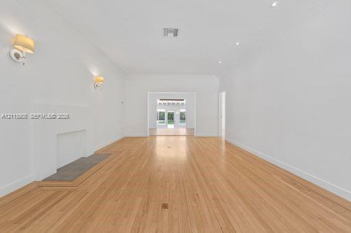 Open-concept interior featuring light wood-finish flooring, a neutral color palette, recessed lighting, wall-mounted light fixtures, and a decorative fireplace.