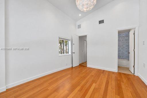 Vaulted ceilings, wood-finish flooring, recessed lighting, and a decorative chandelier