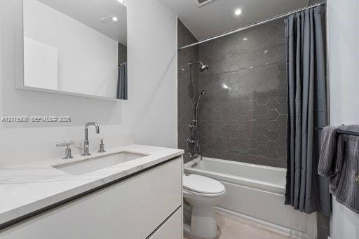 Bathroom featuring a floating vanity with a stone-top integrated sink, chrome widespread faucet, frameless wall-mounted mirror, and a shower-tub combination with dark hexagonal tile surround