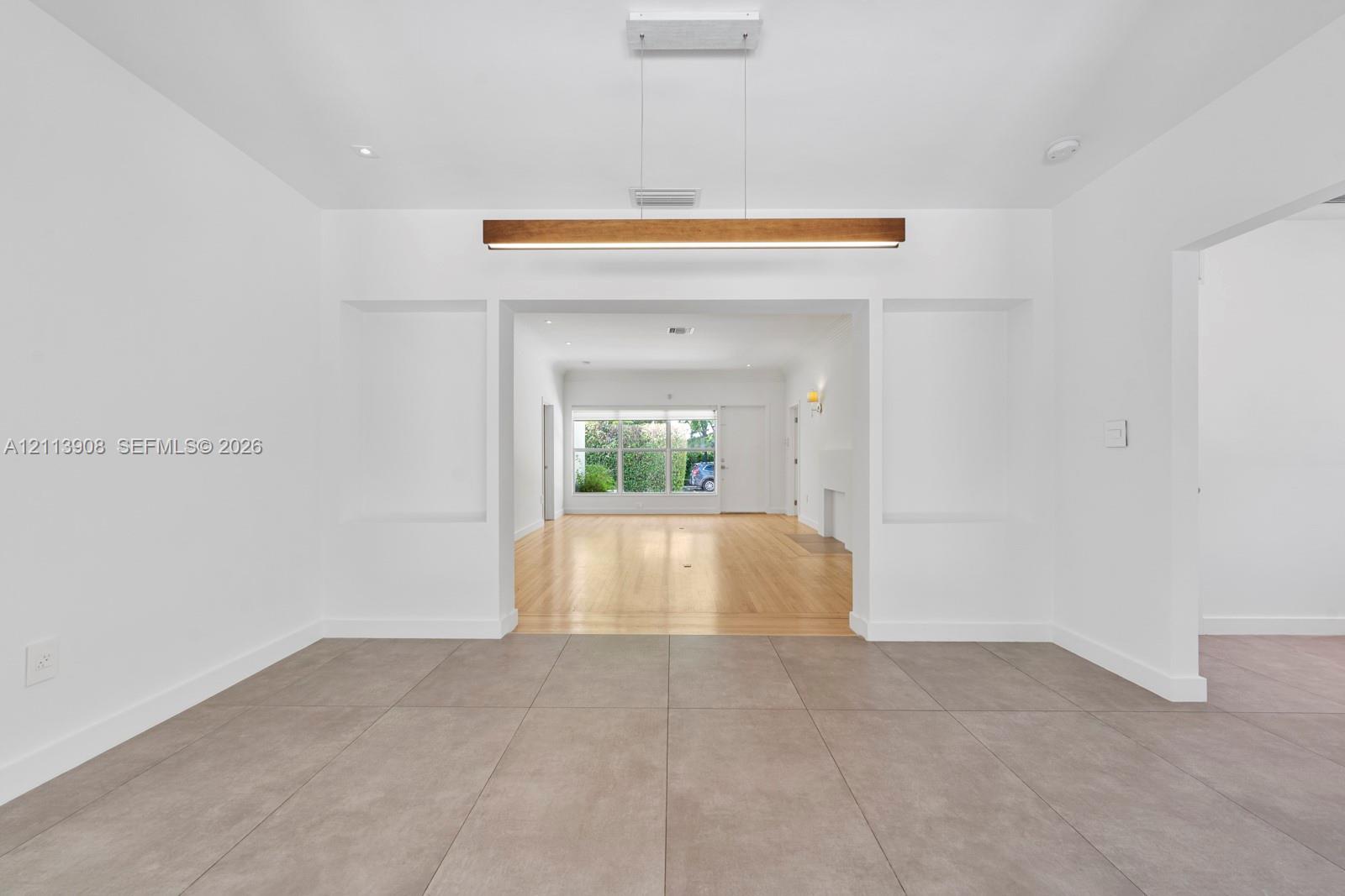 Large-format tile flooring, recessed wall niches, and a linear wood-finish pendant light fixture