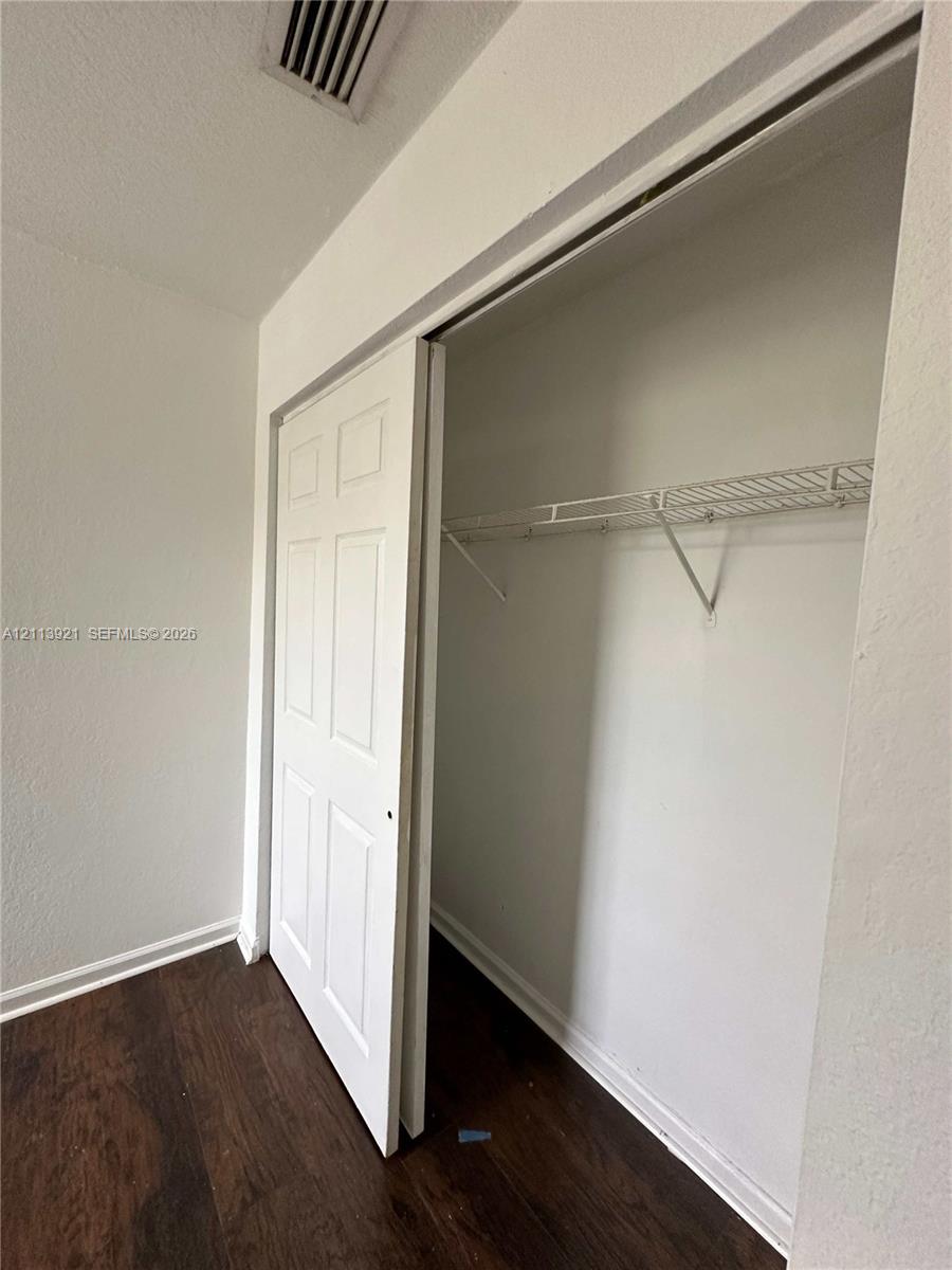 Closet featuring six-panel sliding doors and built-in wire shelving, finished with wood-finish flooring