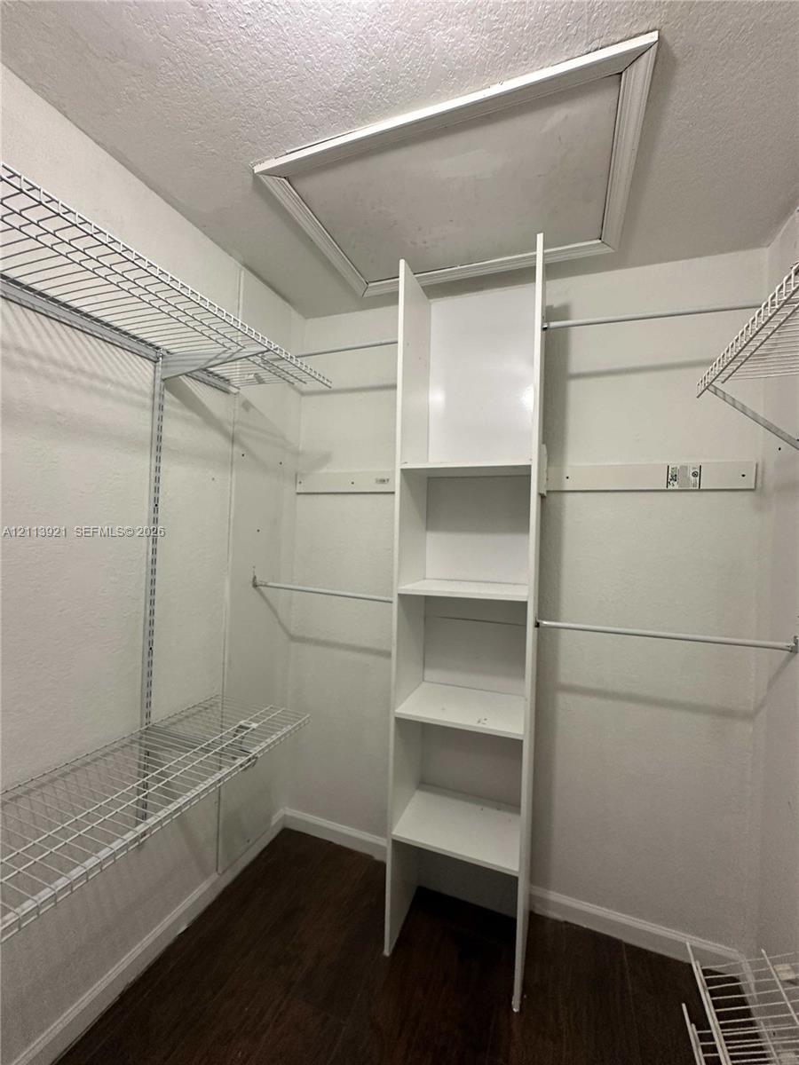 Closet space featuring white wire shelving, a vertical built-in storage tower with four open shelves, and wood-finish flooring