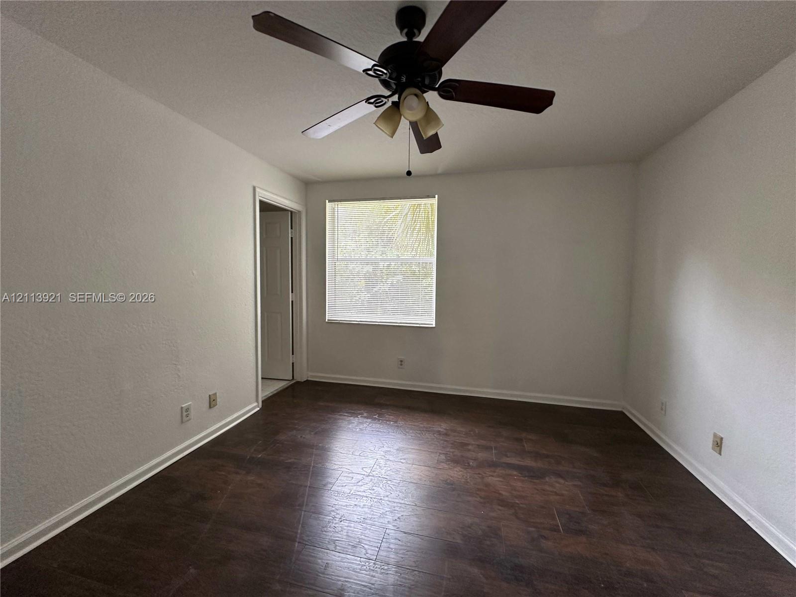 Room featuring wood-finish flooring, a central ceiling fan with integrated lighting, and a single-pane window